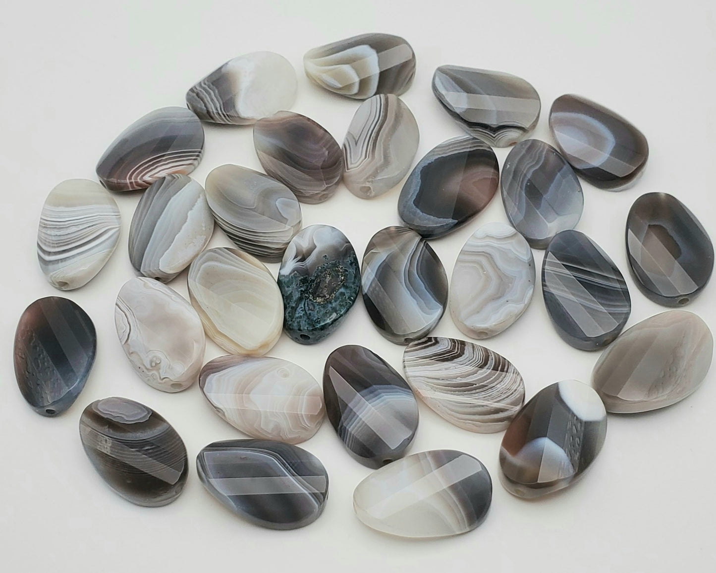 20mm Botswana Agate Curved Faceted Single Beads With each stone showcasing unique natural patterns like stripes and swirls in elegant shades of gray, white, and brown.